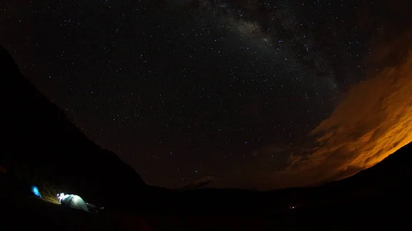 Vista de las carpas iluminadas en una noche estrellada con el volcán Cotopaxi al fondo. Ángulo ancho — Foto de Stock