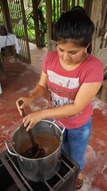 Puerto Quito, Pichincha / Ekvator - 17 Ağustos 2017: kakao çekirdekleri küçük gaz mutfak pişirme genç latin kadın. Kakao çekirdeği Isıtma için el yapımı çikolata yapım sürecinin bir parçası olduğunu