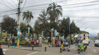 Cayambe, Pichincha / Ekvador - 24 Şubat 2020: Arka planda Matriz Kilisesi ile kentin merkez parkının köşesinde oturan insanlar