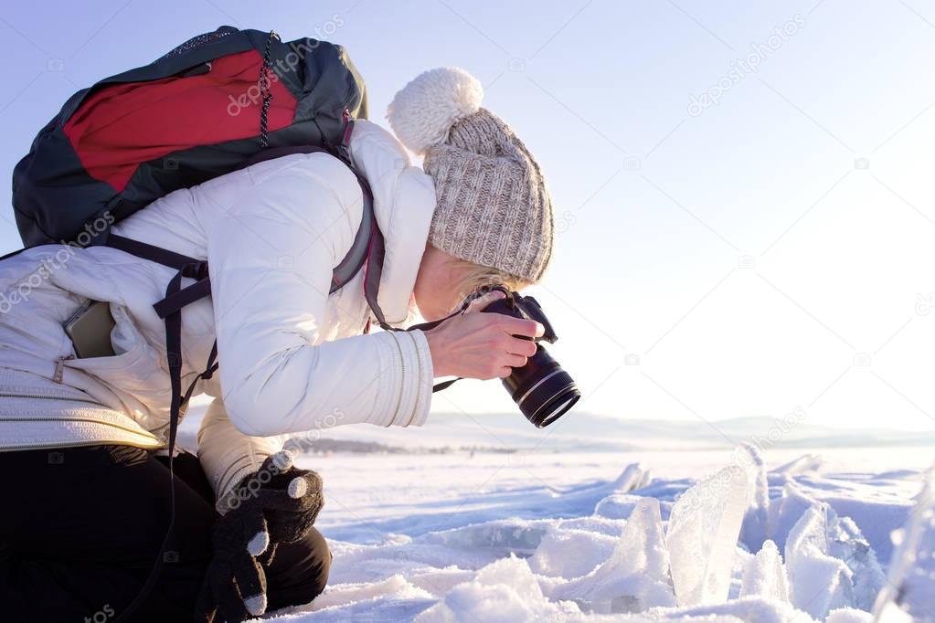 Portrait of female photographer shooting winter landscape next to the frozen lake Baikal. Winter tourism in Russia