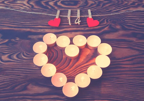 Valentine's day. Heart of candles. Red wooden hearts with pins a