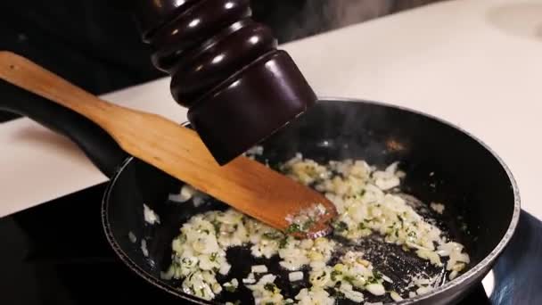 I friterad lök, vitlök och örter tillsätter kocken peppar från pepparskakaren — Stockvideo