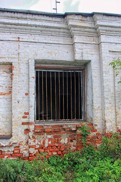 旧的破旧的红砖建筑与一个窗口与铁棍 — 图库照片