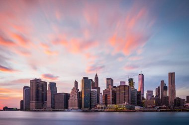 Üzerinde renkli bulutlar olan New York Aşağı Manhattan binalarının manzarası