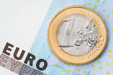 Detail of one euro coin on blue banknote background clipart
