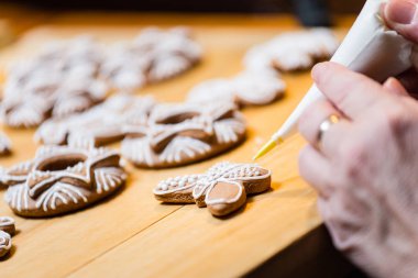 Geleneksel Noel kurabiyelerini süslüyor.