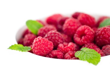 Beyaz kasede taze yeşil nane ile sulu kırmızı ahududu.