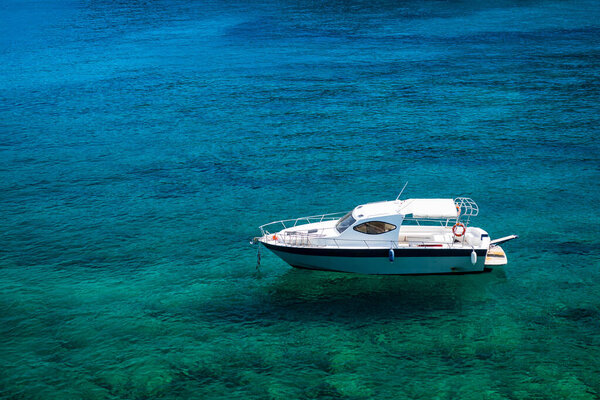 Empty white boat floating on clear turquoise water