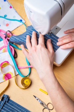 Kadın elleri, koronavirüs pandemisi sırasında yüz maskesini dikmek için dikiş makinesini kullanıyor. Tıbbi malzeme sıkıntısı nedeniyle yerli dikiş.