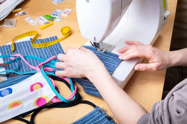 Woman hands using the sewing machine to sew the face mask during the coronavirus pandemia. Domestic sewing due to the shortage of medical materials.