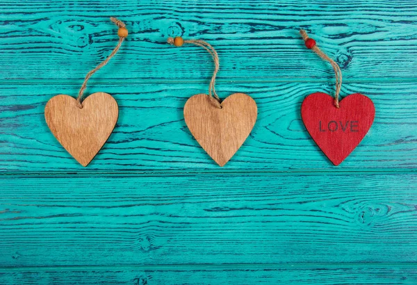 Wooden hearts on a blue background. Pendants made of wood in the form of heart. Copy space.