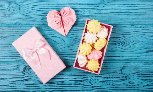 A box with sweets and a heart of paper. Air meringues in a pink gift box.