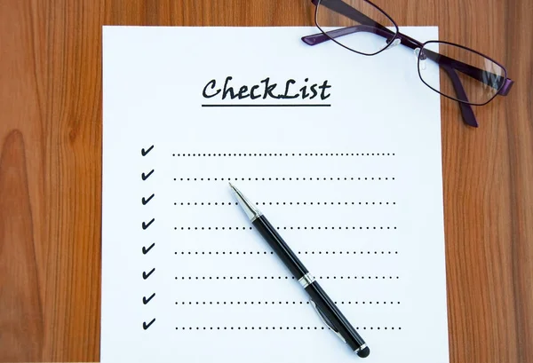 blank checklist on wooden table With a pen and glasses