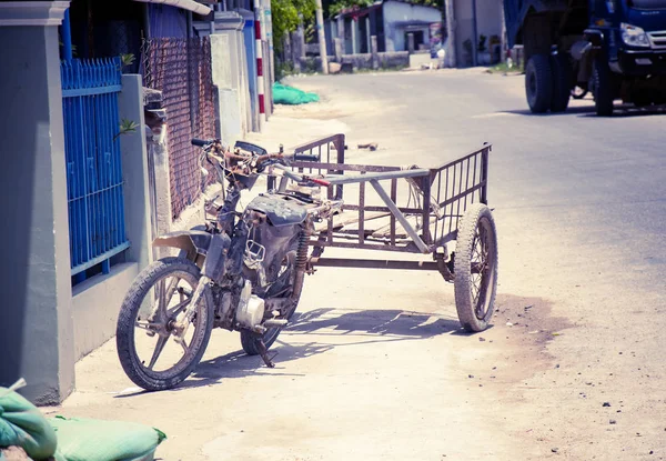 Motobike in the Vietnamese village, adapted for cargo transportation. A picturesque village street. With toning