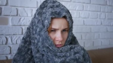 Gri, ekoseli, beyaz, donmakta olan, evinde üşüyen genç bir kadınla kaplanmış, hasta, grip hastası bir kız, içeride titreyen battaniyeye sarılı grip gribi belirtileri. Kapat.. 