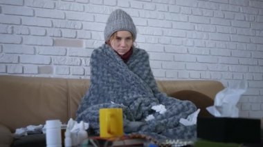 Gri, ekoseli, beyaz kadın şapkalı, eşarplı, evinde üşüyor, hasta hasta hasta bir kız, grip salgını geçiriyor, evde titreyen battaniyeye sarılı..