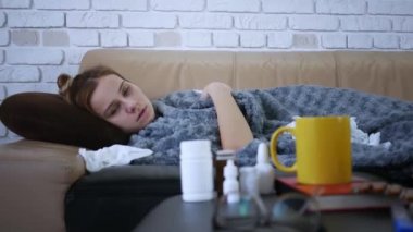 Gri, ekoseli, beyaz kadın şapkalı, eşarplı, evinde üşüyor, hasta hasta hasta bir kız, grip salgını geçiriyor, evde titreyen battaniyeye sarılı..