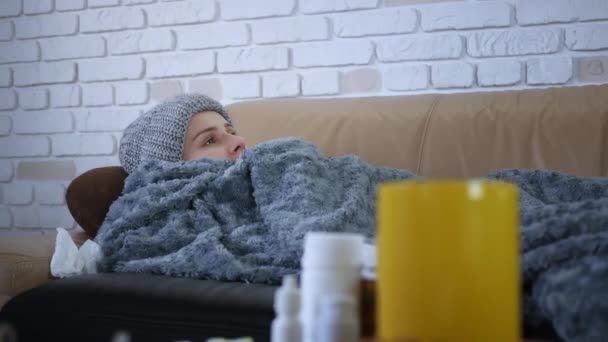 灰色で覆われた帽子とスカーフで若い白人女性寒さを感じる自宅で 病気の女の子熱インフルエンザの温度症状が毛布に包まれて屋内で震え — ストック動画