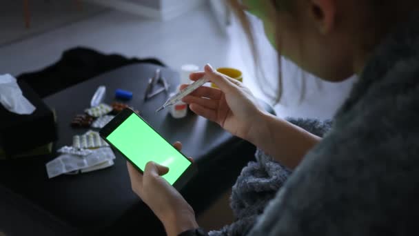 玻璃水银温度计测量温度 女性的手拿着温度计 在网上检查疾病的症状 带有绿色屏幕的电话 — 图库视频影像