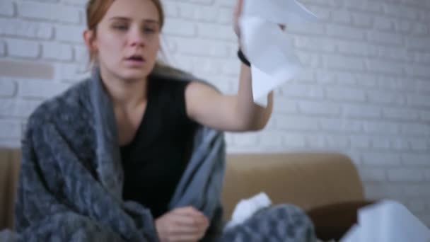 一个年轻的不健康的高加索女人 裹着格子花 在餐巾纸上捂住她的鼻子 因为她感冒了 在家里 — 图库视频影像