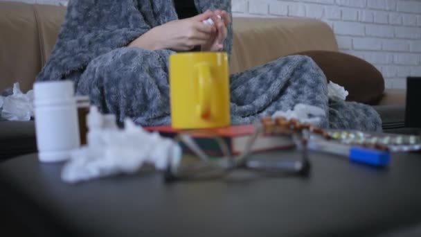 漂亮的年轻高加索女人 鼻子流鼻涕 在家里用鼻腔喷雾器 坐在客厅的沙发上 盖着毛毯 — 图库视频影像