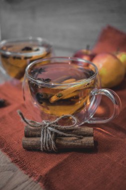 Elma şarabı, meyve suyu, meyve suyu, meyve suyu, baharatlı çay, tarçın çubukları, yıldız anason ve tahta zeminde taze elmalar. Sonbahar ve kış akşamları için sıcak içecek. Kapatın. Mevsimlik sıcak içecek..