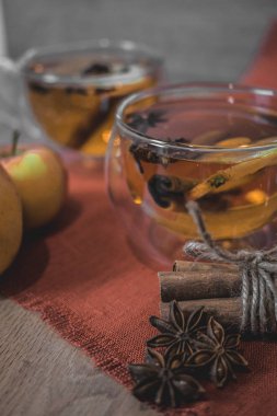 Elma şarabı, meyve suyu, meyve suyu, meyve suyu, baharatlı çay, tarçın çubukları, yıldız anason ve tahta zeminde taze elmalar. Sonbahar ve kış akşamları için sıcak içecek. Kapatın. Mevsimlik sıcak içecek..