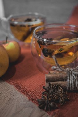 Elma şarabı, meyve suyu, meyve suyu, meyve suyu, baharatlı çay, tarçın çubukları, yıldız anason ve tahta zeminde taze elmalar. Sonbahar ve kış akşamları için sıcak içecek. Kapatın. Mevsimlik sıcak içecek..