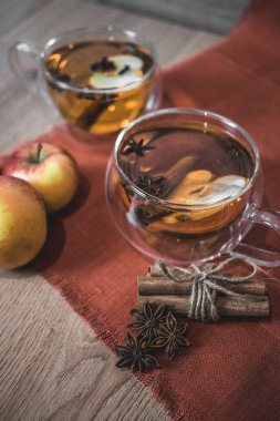 Elma şarabı, meyve suyu, meyve suyu, meyve suyu, baharatlı çay, tarçın çubukları, yıldız anason ve tahta zeminde taze elmalar. Sonbahar ve kış akşamları için sıcak içecek. Kapatın. Mevsimlik sıcak içecek..