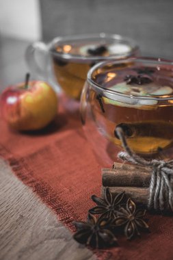 Elma şarabı, meyve suyu, meyve suyu, meyve suyu, baharatlı çay, tarçın çubukları, yıldız anason ve tahta zeminde taze elmalar. Sonbahar ve kış akşamları için sıcak içecek. Kapatın. Mevsimlik sıcak içecek..