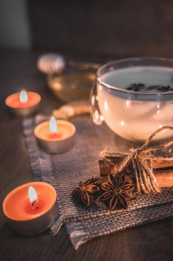 Mum ışığında yakılan geleneksel Hint masala çayı bardağı. Hint masala çayı - sade ahşap arka planda sütlü baharatlı çay, seçici odak, kopyalama alanı. Kapat.. 