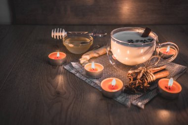 Mum ışığında yakılan geleneksel Hint masala çayı bardağı. Hint masala çayı - sade ahşap arka planda sütlü baharatlı çay, seçici odak, kopyalama alanı. Kapat.. 