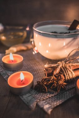 Mum ışığında yakılan geleneksel Hint masala çayı bardağı. Hint masala çayı - sade ahşap arka planda sütlü baharatlı çay, seçici odak, kopyalama alanı. Kapat.. 