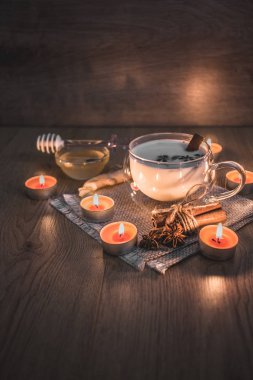 Mum ışığında yakılan geleneksel Hint masala çayı bardağı. Hint masala çayı - sade ahşap arka planda sütlü baharatlı çay, seçici odak, kopyalama alanı. Kapat.. 