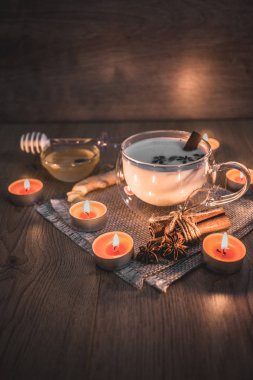 Mum ışığında yakılan geleneksel Hint masala çayı bardağı. Hint masala çayı - sade ahşap arka planda sütlü baharatlı çay, seçici odak, kopyalama alanı. Kapat.. 