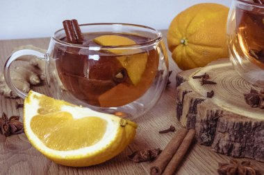 Tarçınlı portakal aromalı çay ve bardakta kakule, portakal ve tarçın çubukları ahşap bir masada. Ahşap arka planda sıcak şarap ve baharatlar. Seçici odaklanma. Kapat.. 