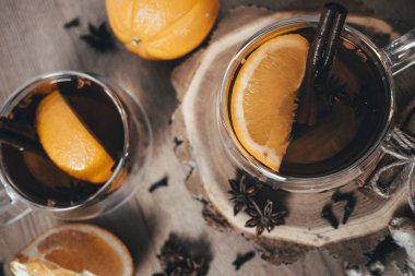 Tarçınlı portakal aromalı çay ve bardakta kakule, portakal ve tarçın çubukları ahşap bir masada. Ahşap arka planda sıcak şarap ve baharatlar. Seçici odaklanma. Kapat.. 