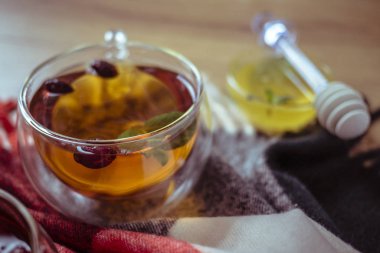 Kırsal masada kurumuş gül kalçası böğürtlen ve gül çayı. Cam bardak çay ve nane yaprağının içinde. Şifalı bitkiler ve şifalı bitkiler. Sonbahar ve kış sezonu geçmişi. Kapat.