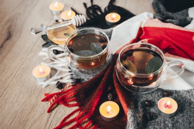 Kurumuş gül kalçası ve arkaplanında taze nane şekeri olan siyah fincanlı çay ve mumlar. Seçici odaklanma. Kapatın. Sonbahar ve kış arkaplanı. 