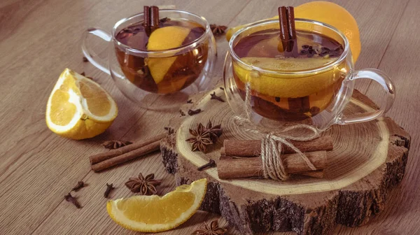 Tarçınlı portakal aromalı çay ve bardakta kakule, portakal ve tarçın çubukları ahşap bir masada. Ahşap arka planda sıcak şarap ve baharatlar. Seçici odaklanma. Kapat.. 