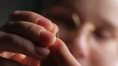 İğnenin deliğine iplik geçirmek. İpliği iğnenin gözüne doğru çekiyor. Genç bir kadın, geceleri evdeki dikiş iğnesinin iğne deliğine beyaz ipliği çekiyor. Kapat.. 