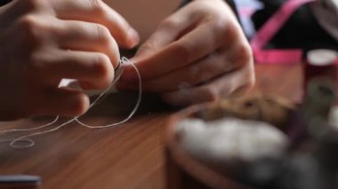 Geceleri evde beyaz pamuk kumaştan yapılmış dikiş yüksüğü içindeki genç bir kadının elleri. Yeniden kullanılabilir koruyucu maskelerinizi yapın. Bir kadının ellerine yakından bak..