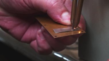 Usta, direnç kaynaklarını kullanarak iki parça metal kaynaklıyor. Mikro elektronikteki direnç kaynağı.