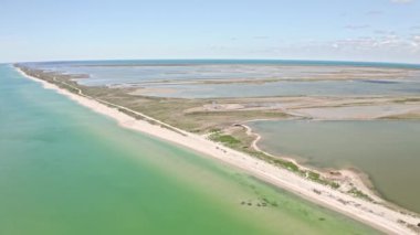Dar tükürük ve deniz manzarası. Güneşli yaz mevsiminde Azov Denizi sığ sularında dik bir kum tepeciği. Güneşin yansımasıyla kumlu adalarda fantastik hava manzarası.