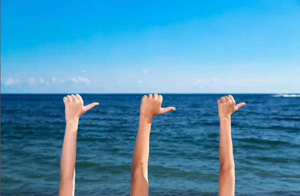 Три руки указывают направление моря на заднем плане — стоковое фото