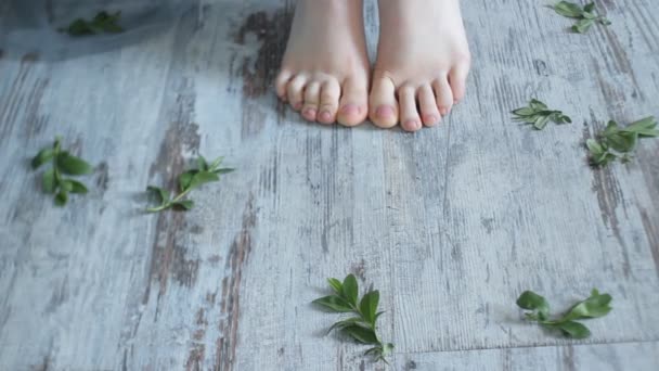 Füße Mädchen auf dem Boden mit grünen Blättern. Bildende Kunst — Stockvideo