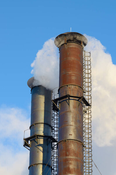 Thick smoke coming from factory chimneys.A beautiful phenomenon on the background of the frosty sky.