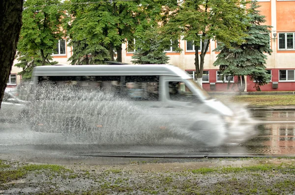 Cars move on asphalt through a huge puddle. Stock Picture