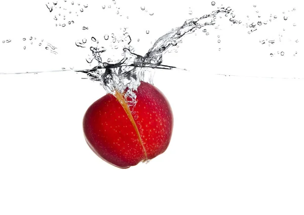 Frutas vermelhas de maçã fazendo respingo na água — Fotografia de Stock