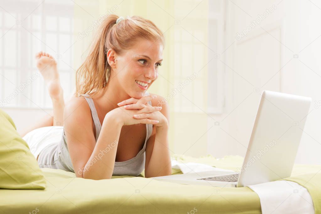 blonde woman using laptop on bed